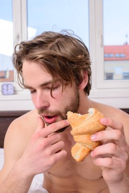 Adam ekmek yapım ürünleri seviyor kruvasan yiyor. Adam tatlı tatlı ısırır. Adam yakışıklı adam yatakta kahvaltı sakallı. Adam kruvasan yatak odalı otel oda pencere arka plan tutar. Her lokma keyfini çıkarın