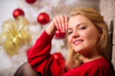 Kış dekorasyonu. Noel bekliyor. Noel ağacı yakınındaki kız giyim kırmızı elbise sit. Kadın mutlu Noel kutlaması. Kış tatil kavramı. Kız rahatla süsler ile Noel ağacı yakınındaki