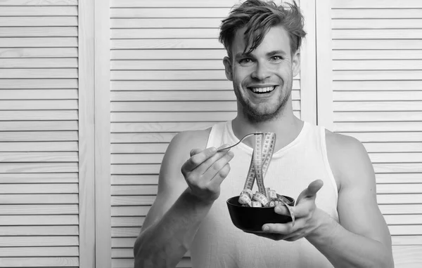 Man holds bowl and fork with measuring tape