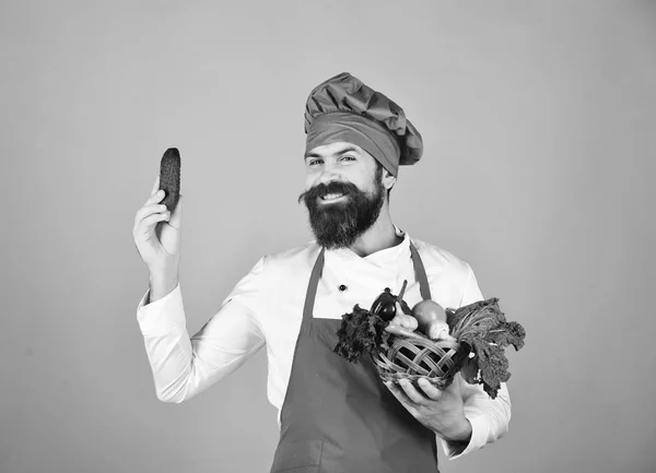 Кухар з посмішкою в бордовій формі тримає огірок — стокове фото