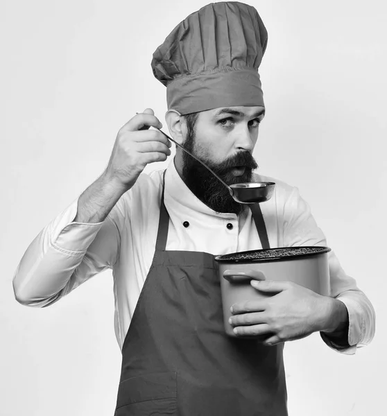 Chef smaakt naar soep. Man met baard houdt rode pot — Stockfoto