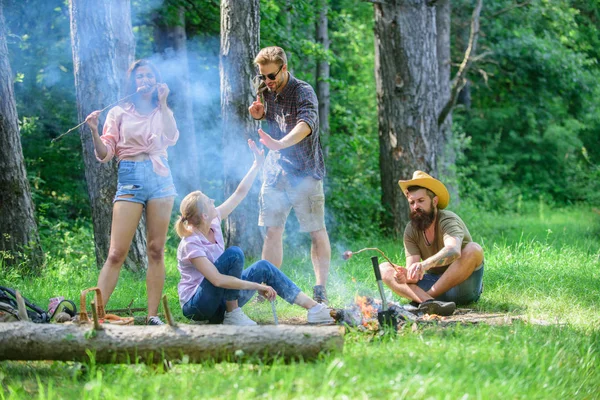 Join summer picnic. Friends meeting near bonfire to hang out and prepare roasted sausages snacks nature background. Gathering for great picnic. Company having fun while roasting sausages on sticks