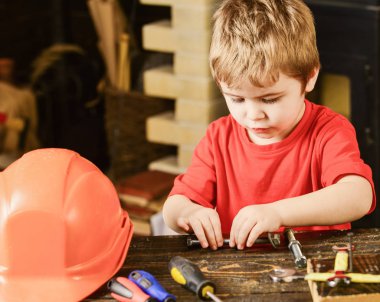 Çocuk Çocuk tamirci oynamak. Yürümeye başlayan çocuk meşgul yüzündeki evde atölyede civata ile oynuyor. Kavram handcrafting. Çocuk şirin ve sevimli ile oynarken Oluşturucusu'nu veya repairer, onarımı veya handcrafting cıvata