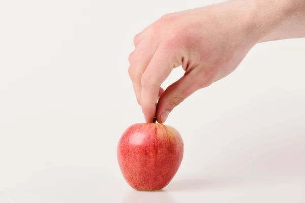 La mano masculina sostiene la manzana roja clara. Manzana sobre fondo claro — Foto de Stock