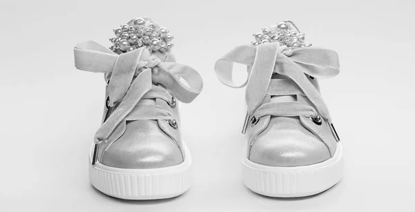 Взуття для дівчаток або жінок, прикрашене перловими намистинами. Комфортна концепція взуття. Милі черевики на жовтому тлі. Пара блідо-рожевих жіночих кросівок з оксамитовими стрічками — стокове фото