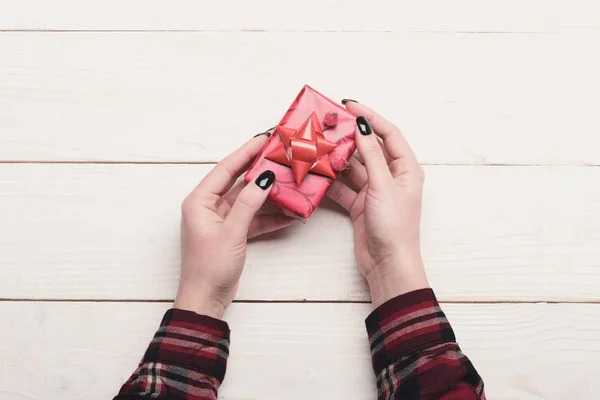 Mãos femininas segurar caixa envolto em papel vermelho com arco — Fotografia de Stock