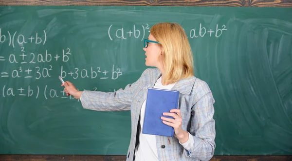 Lo que hace un gran maestro. Profesor mujer inteligente con libro explicar el tema cerca de pizarra. El profesor de escuela explica bien las cosas y hace que el tema sea interesante. Enseñanza de actividades complejas y multifacéticas — Foto de Stock