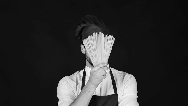 Chef with hidden face holds bunch of spaghetti