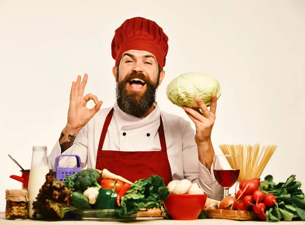 Chef prepares meal showing ok sign. Man with beard