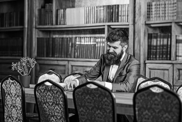 Interesting book concept. Happy man sits in vintage interior and enjoys relaxing reading. Bearded man in formal outfit. Mature man with smiling face has tea. Laugh, relax, pleasure, leisure, hobby