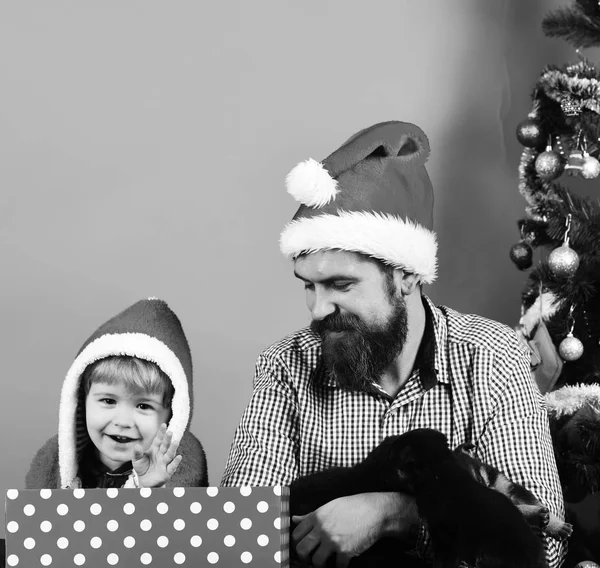 Uomo e ragazzo a Babbo Natale giocano con i cuccioli — Foto Stock