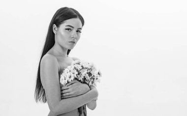 Bayan göğüsler üzerinde beyaz izole çiçekli kapsar. Kanser meme kavramının. Sakin yüz çıplak kız papatya çiçeği göğüs önünde tutar. Kadın göğüslerini buket kapaklarla gizleme