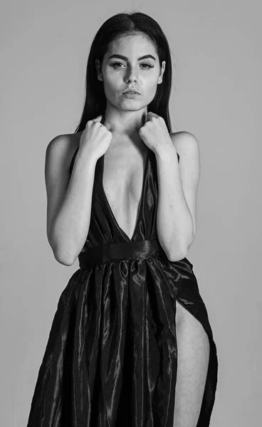 Σέξι ντεκολτέ έννοια. Γυναίκα σε κομψό μαύρο φόρεμα βράδυ με ΝΤΕΚΟΛΤΕ, γκρι φόντο. Ελκυστική κοπέλα φοράει ακριβά μοντέρνες βραδινό φόρεμα με σκίσιμο ερωτικό. Κυρία, σέξι κορίτσι με φόρεμα — Φωτογραφία Αρχείου