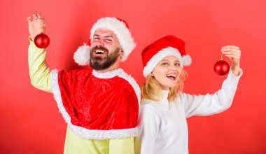 Çift Noel Noel Baba kostüm süsleme topu tutun. Christmas dekorasyon gelenek. Kadın ve santa şapka içinde sakallı adam arka arkaya Noel bekleyen hazır. Noel kutlamaları kavramı