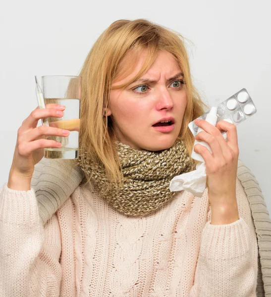 Способы быстро почувствовать себя лучше. Средства от головной боли и гриппа. Избавься от гриппа. Женщина носит теплый шарф из-за болезни или гриппа. Девушка держит стеклянные таблетки воды и капли носа термометра. Быстрое облегчение — стоковое фото
