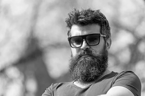 Hipster met baard en snor op strikte gezicht, natuur achtergrond, intreepupil. Bebaarde man draagt stijlvolle zonnebril. Man met baard ziet er stijlvol en zelfverzekerd op zonnige dag. Mode en stijl concept — Stockfoto