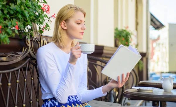 Mujer tomar café terraza al aire libre. Concepto matutino perfecto. Chica beber café mientras lee nuevo libro bestseller de autor popular. Taza de café y libro interesante mejor combinación fin de semana perfecto — Foto de Stock