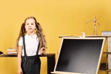 Kız kopya alanı tahtaya yazar. Düşünceli yüz ile kız öğrenci