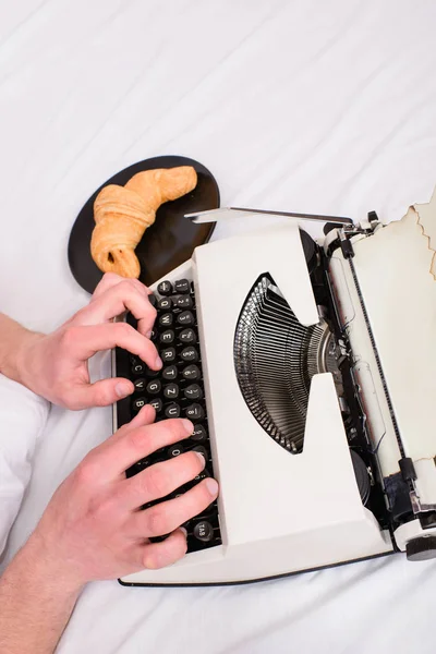 Scrittore autore abituato alla vecchia macchina stile invece di gadget digitale. Creare un nuovo capitolo utilizzare la macchina da scrivere. Concetto di ispirazione mattutina. Mani scrittore letto bianco biancheria da letto lavorando sul nuovo libro — Foto Stock