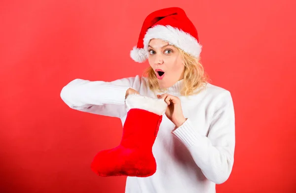 Conceito de meia de Natal. Menina cara alegre confira presente na meia de Natal. Verifique o conteúdo do Natal meia o que ela recebeu. Mulher em santa chapéu desembalagem presente de Natal vermelho fundo — Fotografia de Stock