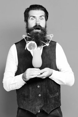 yakışıklı sakallı adam uzun sakal ve bıyık renkli tüplerde ile şık vintage süet deri yelek kırmızı studio arka plan üzerinde alkollü kokteyl bardak tutan sürpriz yüzündeki saçlı