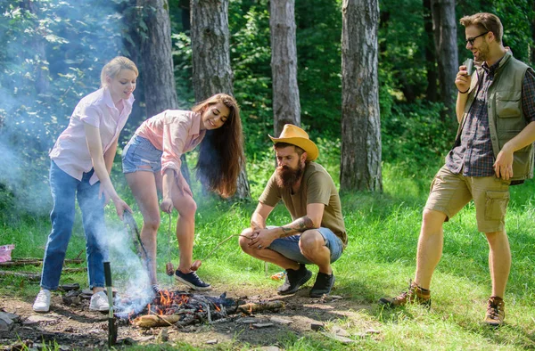 Company hikers at picnic roasting sausages on sticks. Friends prepare roasted sausages snacks nature background. Camping traditional meal prepared on fire with smoky aroma. Take a break to have snack — Stock Photo, Image
