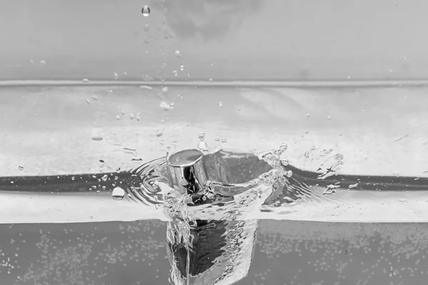 Nagellackflasche unter Wasser mit transparenten Blasen und Wasserspritzern, blauer Hintergrund. Nagellack fällt in reines, transparentes Wasser. Schönheits- und Pflegekonzept — Stockfoto