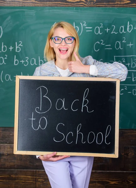 Super début d'année scolaire. Meilleures façons d'accueillir les élèves à l'école. La maîtresse garde l'inscription au tableau noir à l'école. C'est encore l'heure de l'école. Professeur heureux d'accueillir l'élève — Photo