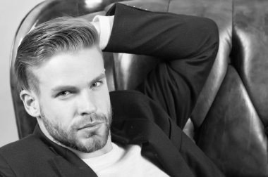 İşadamı emin yüz, deri sandalye arka plan sakallı. Metroseksüel kavramı. Adam yakışıklı ve bakımlı tıraşsız adam görünüyor sakallı. Adam çekici görünümü ile ilgili, sağlıklı ciltle pürüzsüz umurunda değil.