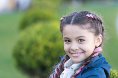 Parlak detay ekle. Şirin örgü ören küçük bir kız doğayı yakından takip ediyor. Kanekalon, şirin çocuk örgüleri içinde. Modern saç modeli konsepti. Pembe kanekalonlu örgülü saçlı kız.