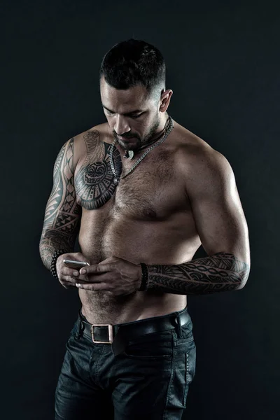 O meu telemóvel é o meu melhor amigo. Homem com tatuagem no corpo muscular. O homem musculoso usa o telemóvel. Tatuagem e arte corporal. Esporte é tudo sobre jogar e competir — Fotografia de Stock