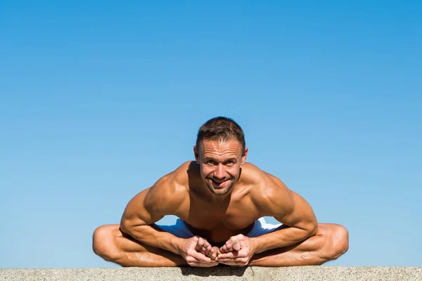 Практика йоги помогает найти гармонию и баланс. Человек практикует йогу на голубом фоне неба. Достиг душевного спокойствия. Концепция медитации и йоги. Йога помогает найти баланс и объединиться с природой — стоковое фото