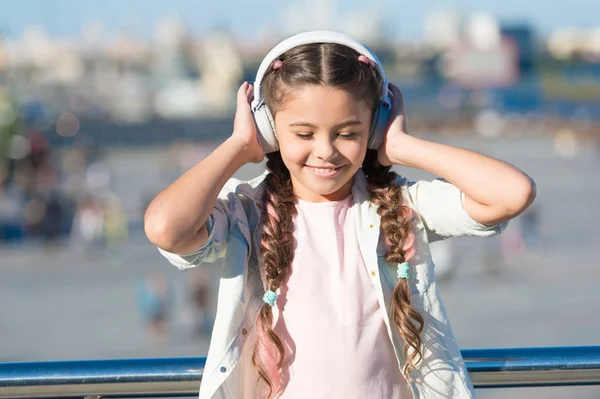 Bambina ascoltando musica godere di canzone preferita. Ragazza con cuffie sfondo urbano. L'influenza positiva della musica. Bambino ragazza godendo di musica auricolari moderni. Infanzia e musica adolescenziale gusto — Foto Stock