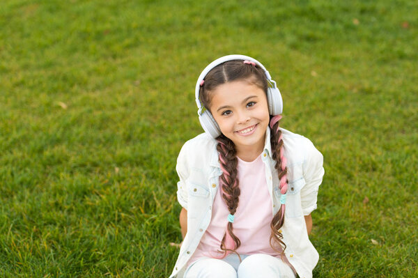 Girl with headphones nature background. Positive influence of music. Child girl enjoying music modern earphones. Childhood and teenage music taste. Little girl listening music enjoy favorite song