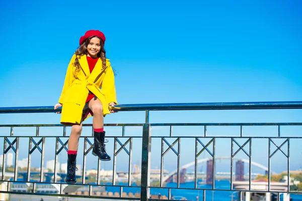 O acessório brilhante garante o humor alegre. Faça esta queda mais brilhante com acessório. Conceito de queda brilhante. Kid menina casaco amarelo boina vermelha desfrutar queda sentar corrimão azul céu fundo — Fotografia de Stock