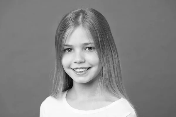 Menina no rosto sorridente com cabelos longos usa camisa branca, fundo violeta. Menina gosta de olhar bonito, elegante e elegante. Miúda com cabelo comprido parece adorável. Penteado e conceito de cuidado do cabelo — Fotografia de Stock