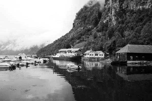 Geiranger, Noruega - 25 de enero de 2010: casas de pueblo, barcos en el puerto marítimo en el paisaje de montaña. Transporte de agua, barcos. Destino de viaje, turismo. Vacaciones, viaje, ansia de viajar . —  Fotos de Stock