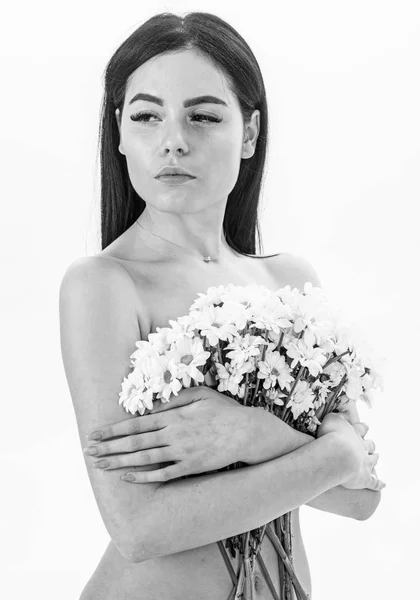 Menina no rosto calmo nu contém flores de camomila na frente de seios. Conceito de cosméticos naturais. Mulher com pele lisa e saudável parece atraente. Senhora cobre seios com flores, isoladas em branco — Fotografia de Stock