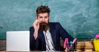 Öğretmen formal Giyim tablo sınıf kara tahta arka plan otur. Konsantre öğretmen Olgun öğretmen dikkatle dinlerken sakallı. Öğretmen dinleme cevap veya rapor. Ayrıntılara dikkat