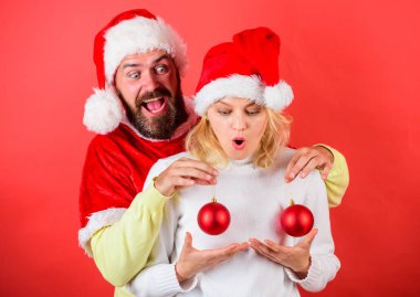 Noel mucize kavramı. Plastik cerrahi. Çift heyecanlı Noel topları tutmak. Adam Noel Baba şapkası Noel süs önünde kadın meme topları tutun. Noel topları sembolü kadın meme implantı