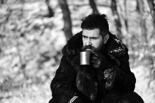 El hombre con abrigo de piel sostiene una copa de metal. Chico en el bosque —  Fotos de Stock