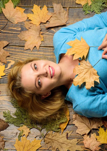 Girl blonde lay on wooden background with orange leaves top view. Woman pretty lady enjoy cozy season hold autumn dry leaves. Fall atmosphere attributes. Fall and autumn season concept — Stock Photo, Image