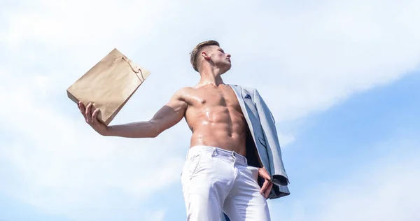 販売シーズンです。男の筋肉アスリート ショッピング バッグ空背景を保持します。ホット販売と割引。魅力的なマッチョの男は、茶色の紙で作った買い物袋を運ぶ。エコ パッケージ。店員のコンセプト — ストック写真