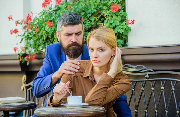 Pareja enamorada bebe café expreso durante la pausa para el café. Mujer y hombre con caras serias toman café en la cafetería. Concepto de problemas de relaciones. Chica y barbudo chico tienen café café terraza fondo — Foto de Stock