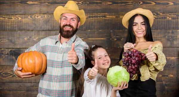 素朴なスタイルで家族農民市場秋の収穫。収穫祭のコンセプトです。収穫の木製の背景を持つ家族経営の農家です。両親と娘を祝う収穫休日カボチャの野菜果物 — ストック写真