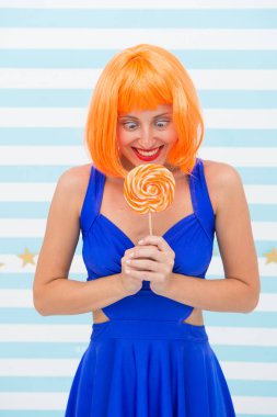 Turuncu saçlı moda kızı eğleniyor. Elinde lolipop olan mutlu poster modeli. Lolipopu olan havalı bir kız. Seksi bir kadın. Oyuncu modunda çılgın bir kız. Deli kız. Oyun zamanının tadını çıkarıyorum. Deliriyorum