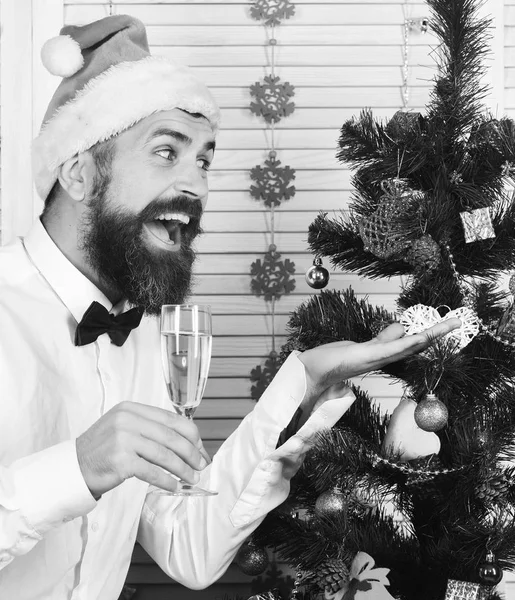 髭を生やした男がシャンパングラスを持ち、モミの木を見せる — ストック写真