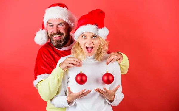 Cirurgia plástica. Homem Papai Noel segurar bolas enfeite de Natal na frente de seios femininos. Bolas de Natal símbolo implantar seios femininos. Casal animado segurar bolas de Natal. Conceito milagre de Natal — Fotografia de Stock