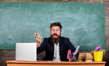 Öğretmen düşük bilgi seviyesini merak ediyordu. Sen neden bahsediyorsun? Hiç hoş değil. Ne aptalca bir düşünce. Erkek sakallı öğretmen ifadeyi merak ediyor. Sınıfın tahtasında oturuyor.