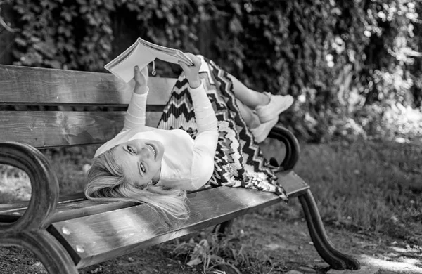 Mädchen lag Bank Park entspannen mit Buch, grüne Natur Hintergrund. Frau verbringt Freizeit mit Buch. Mädchen lesen im Freien, während sie es sich auf der Bank gemütlich machen. Zeit für Selbstverbesserung. Dame glücklich Gesicht genießen Sie die Lektüre — Stockfoto